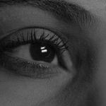 Black and white closeup part of face of anonymous dreamy enigmatic female with brown eyes and long eyelashes looking away thoughtfully